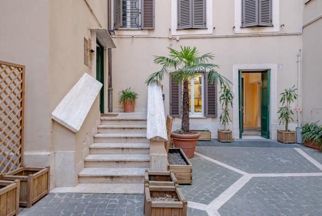 Cortile interno con piante in vaso e scale di marmo.